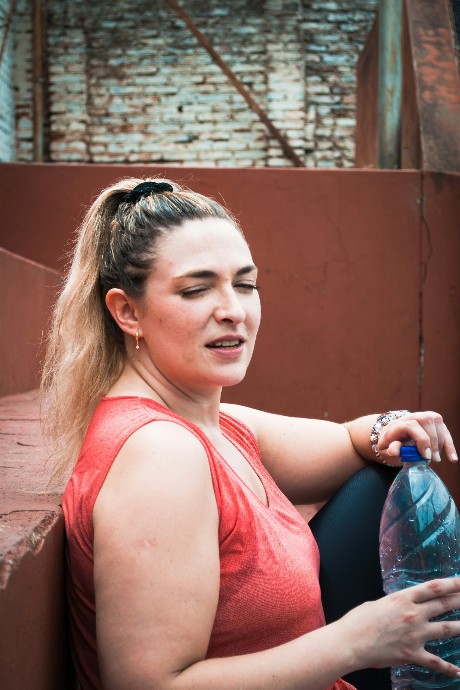 Woman sitting outdoors on a bench in spring holding a water bottle