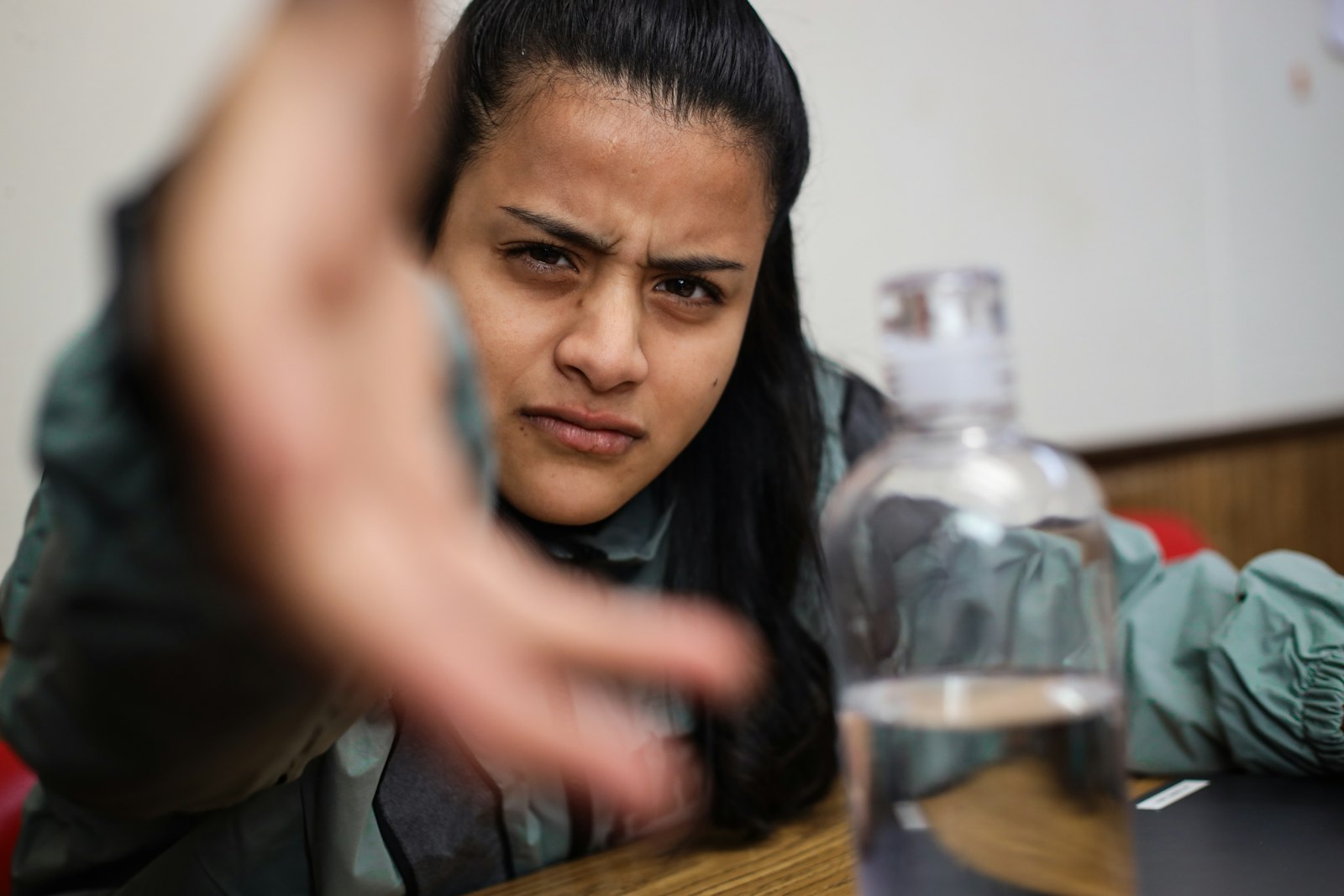 Woman indoors reaching for a bottle of water during a busy day