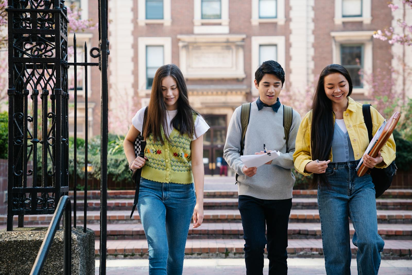 Smiling university students walking across campus with backpacks during a spring visit day