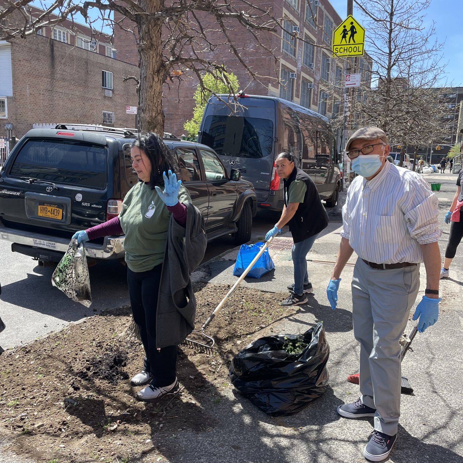 Volunteers doing an outdoor Earth Day cleanup in a park with gloves, trash bags, and water nearby