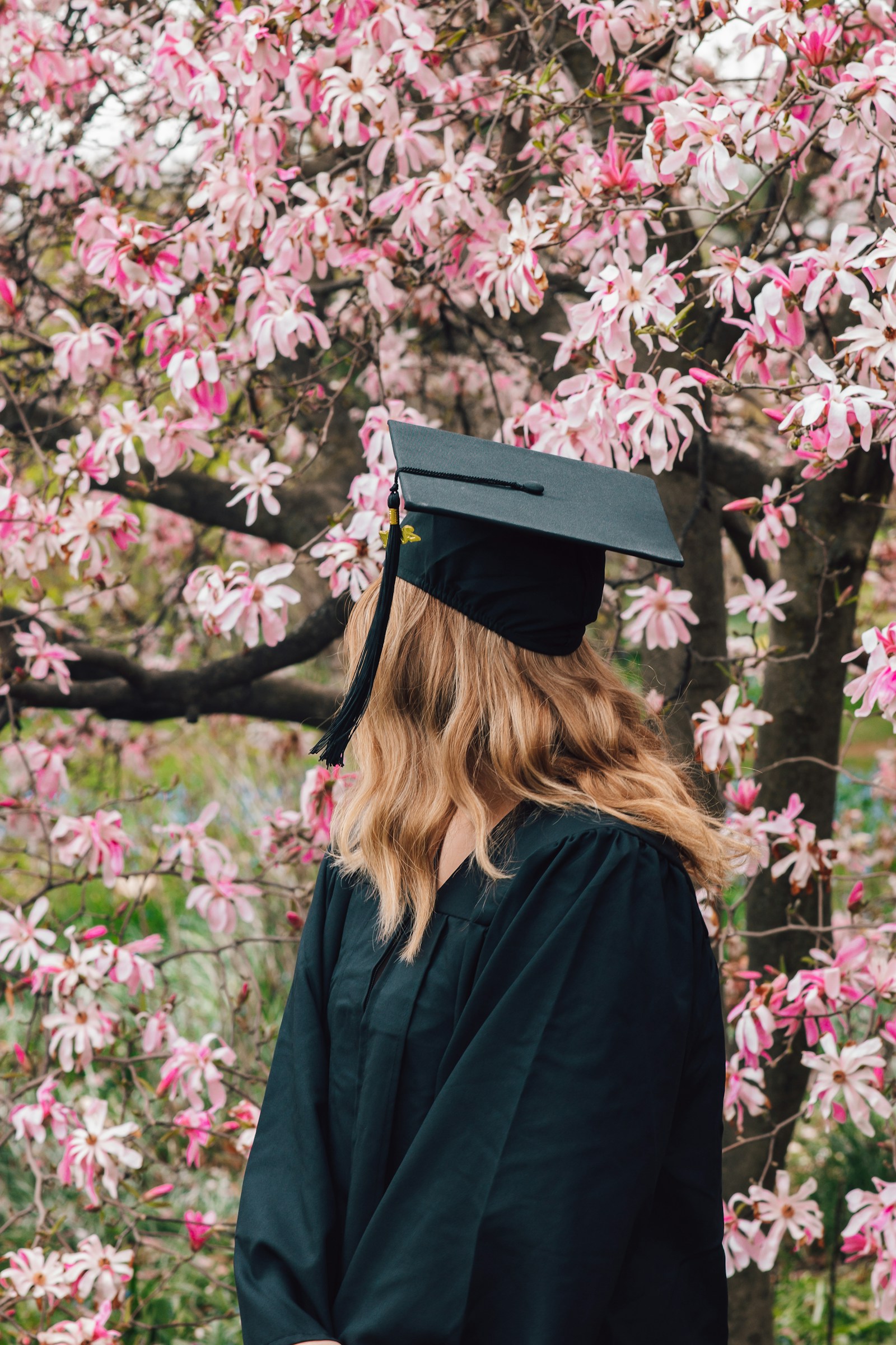 Graduate standing outdoors in cap and gown during a spring graduation ceremony
