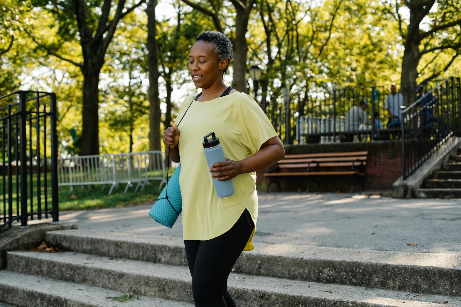Woman walking outdoors on a sunny spring path while carrying a water bottle