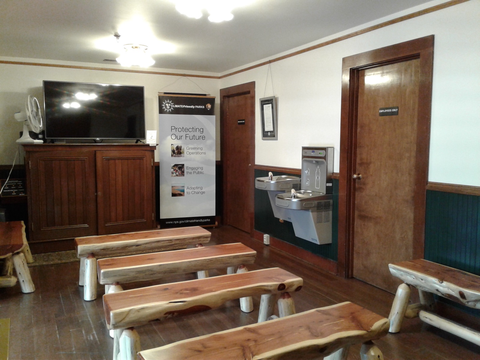 A bottle filling station inside a park visitor area with benches nearby